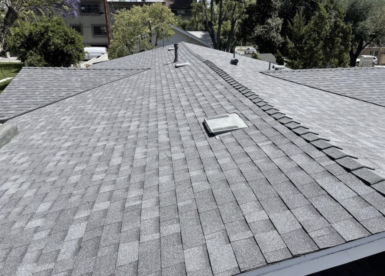Completed gray dimensional shingle roof with finished ridge caps and vents